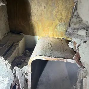 Leftover wood form boards exposed beneath a masonry fireplace hearth in a Glencoe home
