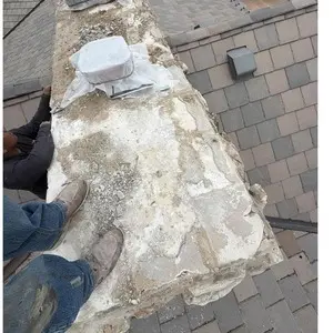 Worn, uneven concrete crown on top of a stone chimney before the rebuild