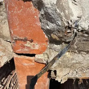 Deteriorated upper chimney masonry above the roofline before a partial rebuild