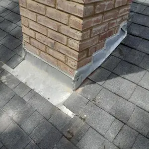 Resealed chimney flashing where the chimney meets the roof shingles