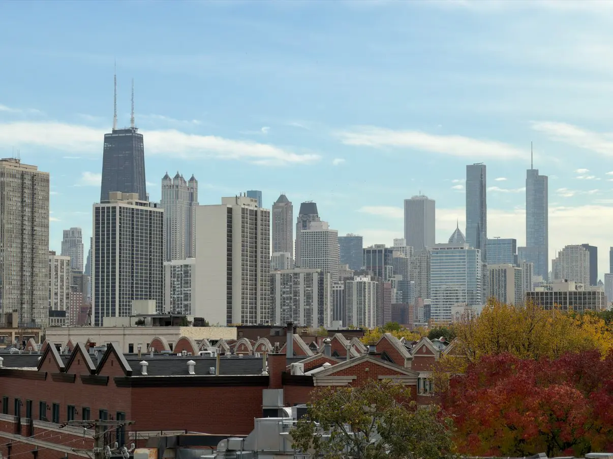 Chicago skyline and dense residential buildings near a difficult-access dryer vent project