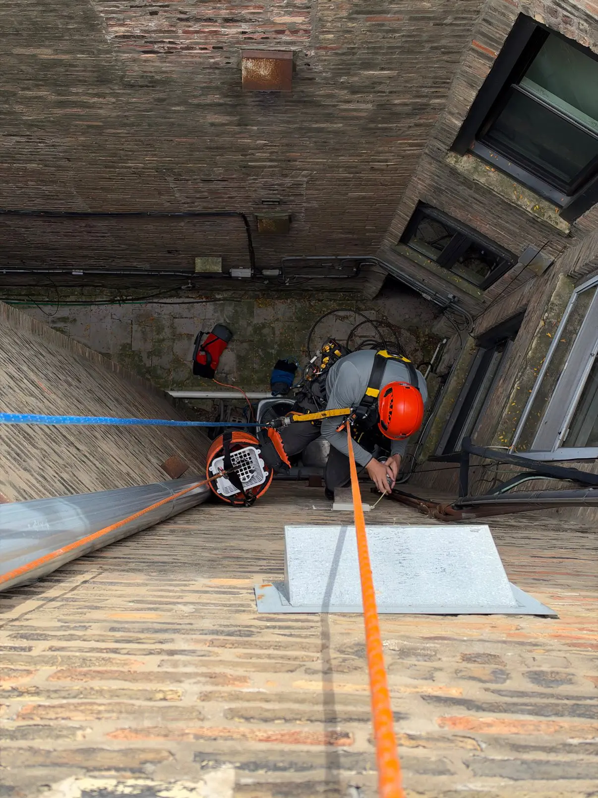 Rope-access technician working beside a high exterior dryer vent on a Chicago masonry building