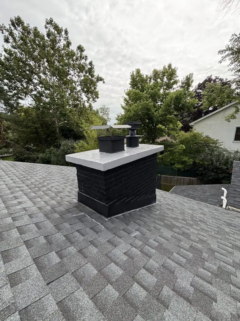 Finished chimney crown with a fresh white crown coating and black mesh flue caps on a painted brick chimney