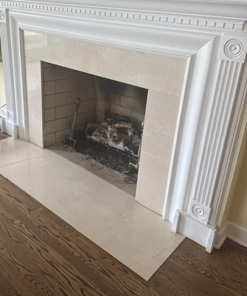 Marble-surround fireplace with a white mantel and a gas log set in the firebox
